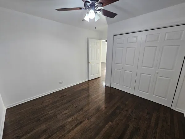 an empty room with wooden floor fan and window