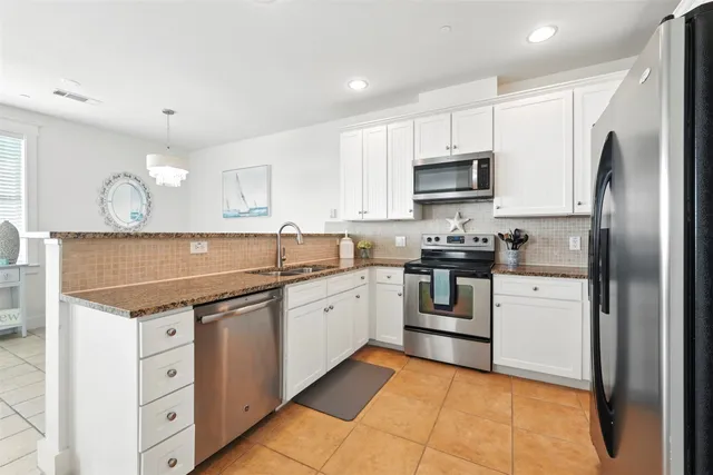 a kitchen with granite countertop a sink stainless steel appliances and cabinets