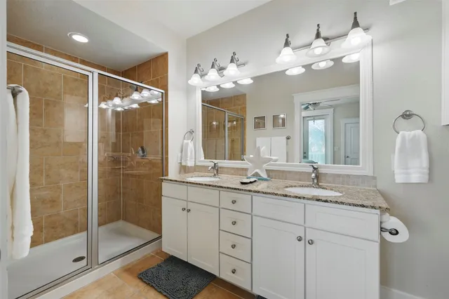 a bathroom with a double vanity sink mirror and shower
