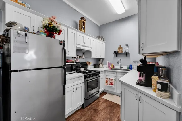 a kitchen with stainless steel appliances a stove a sink dishwasher and cabinets with wooden floor