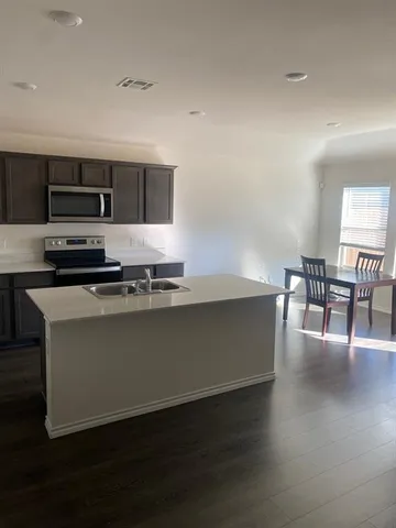 a kitchen with stainless steel appliances a kitchen island hardwood floor sink stove dining table and chairs