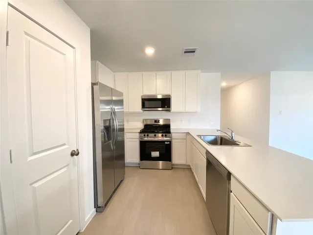 a kitchen with a sink a counter top space stainless steel appliances and cabinets
