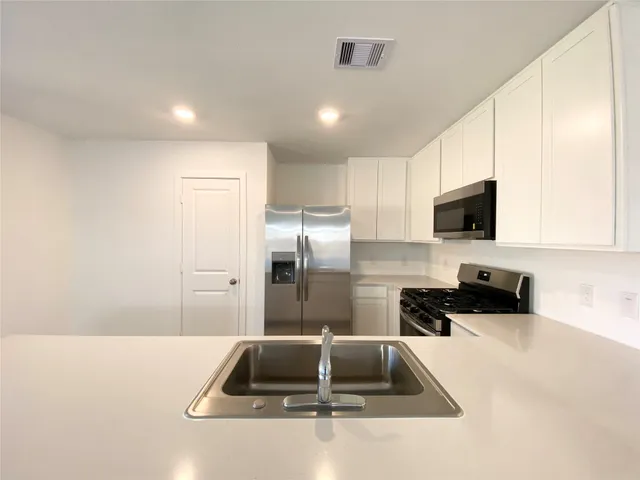 a kitchen with a sink a counter top space cabinets and stainless steel appliances