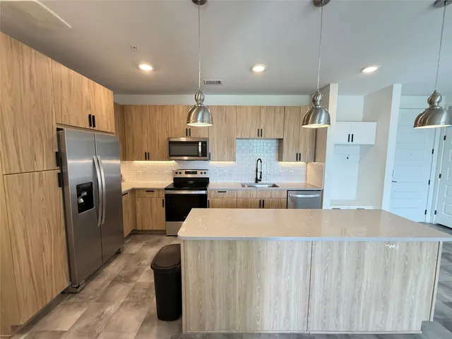 a large kitchen with a large counter top appliances a sink cabinets and a counter top space