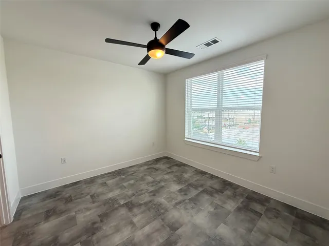 an empty room with ceiling fan and window