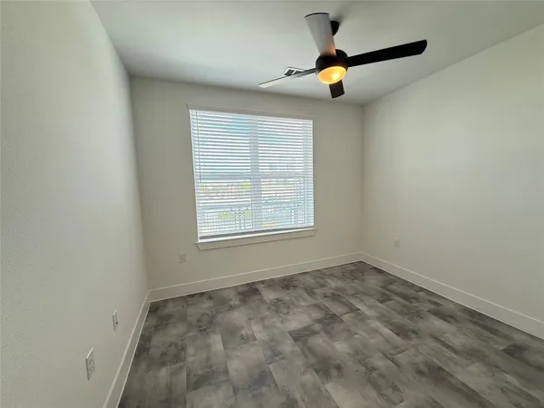 an empty room with ceiling fan and window