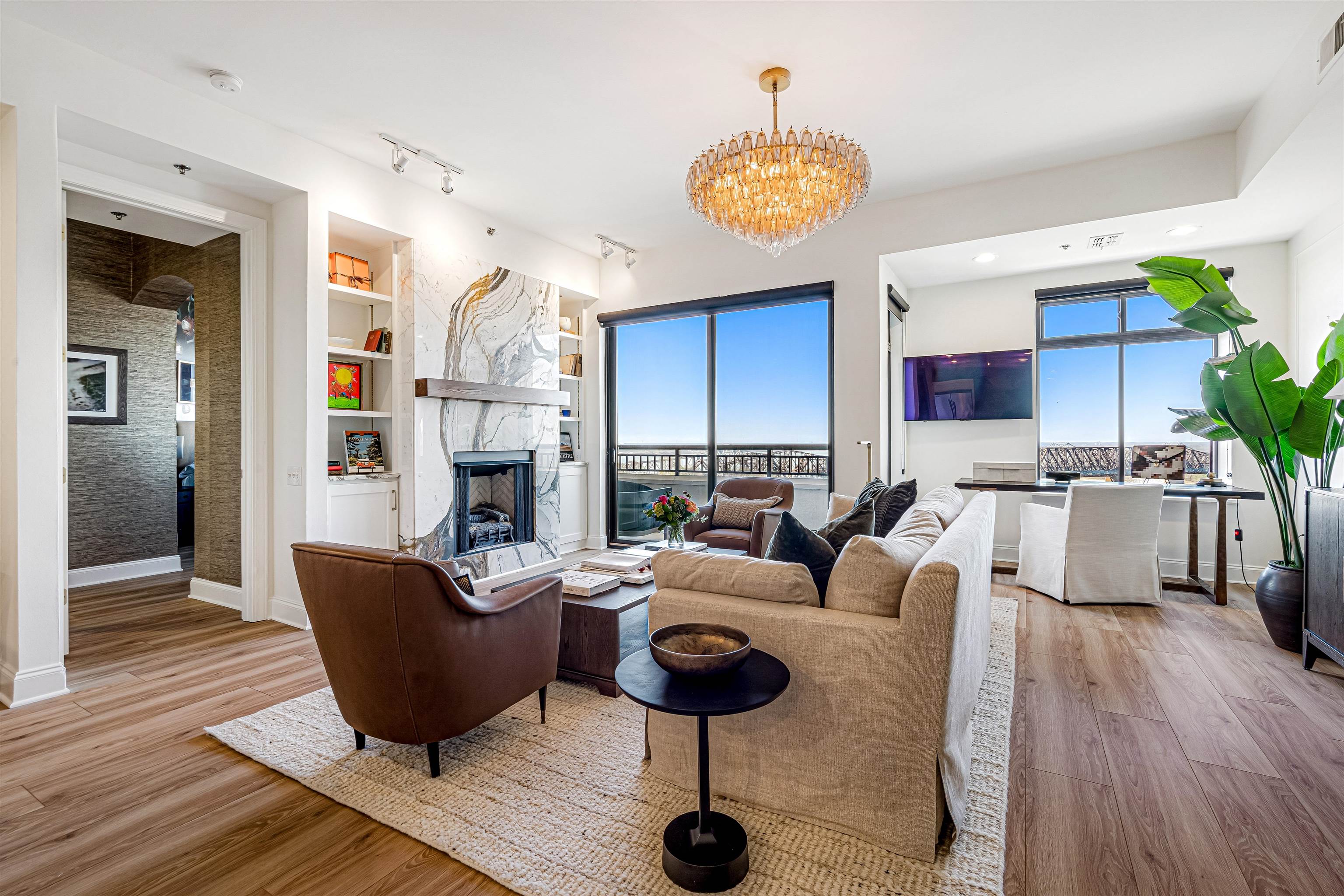 Living area featuring built in shelves, a fireplace, light wood-style flooring, and suspended lighting