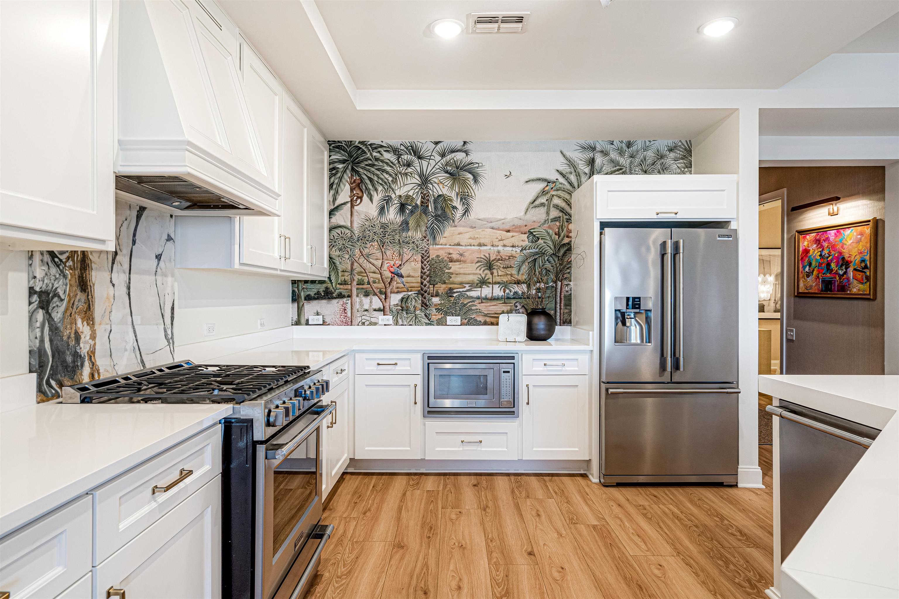 717 Riverside Drive, Unit 1205 Memphis, TN 38103 - Photo 29 of 33 Kitchen featuring stainless steel appliances, white cabinetry, light wood finished floors, wallpapered walls, and light stone counters