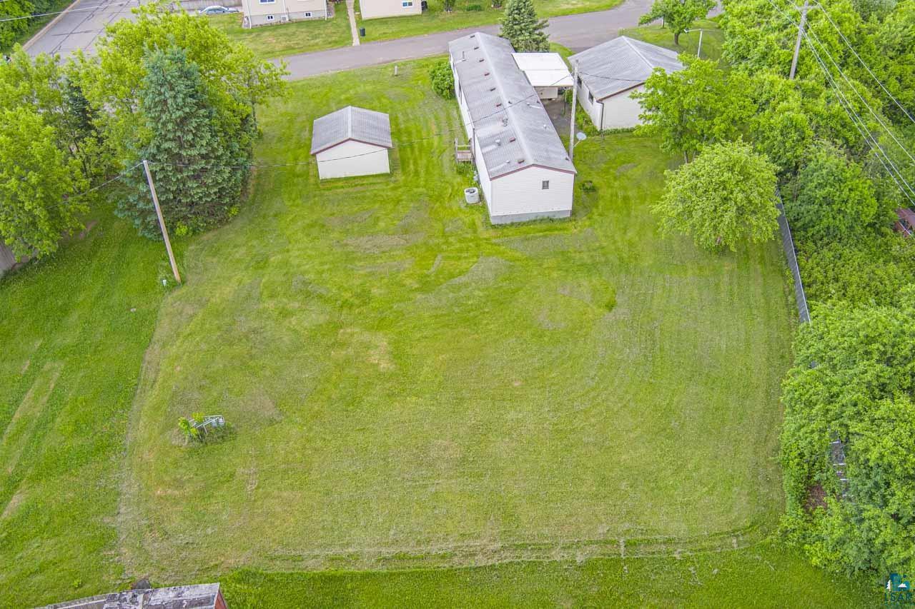 705 4th Street North Biwabik, MN 55708 - Photo 28 of 29 Expansive green lawn surrounds the property, featuring a long single-story structure with a gray roof and light-colored siding