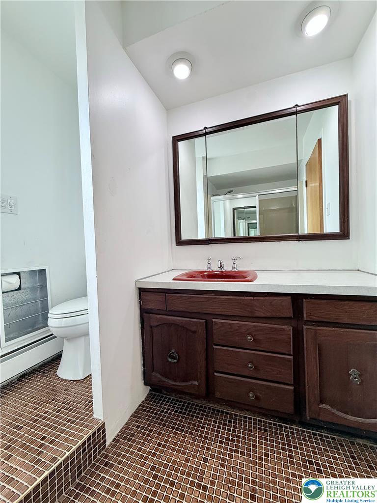 5540 Main Street Whitehall, PA 18052 - Photo 23 of 53 A compact bathroom offers a vanity with ample storage and a vibrant red sink.