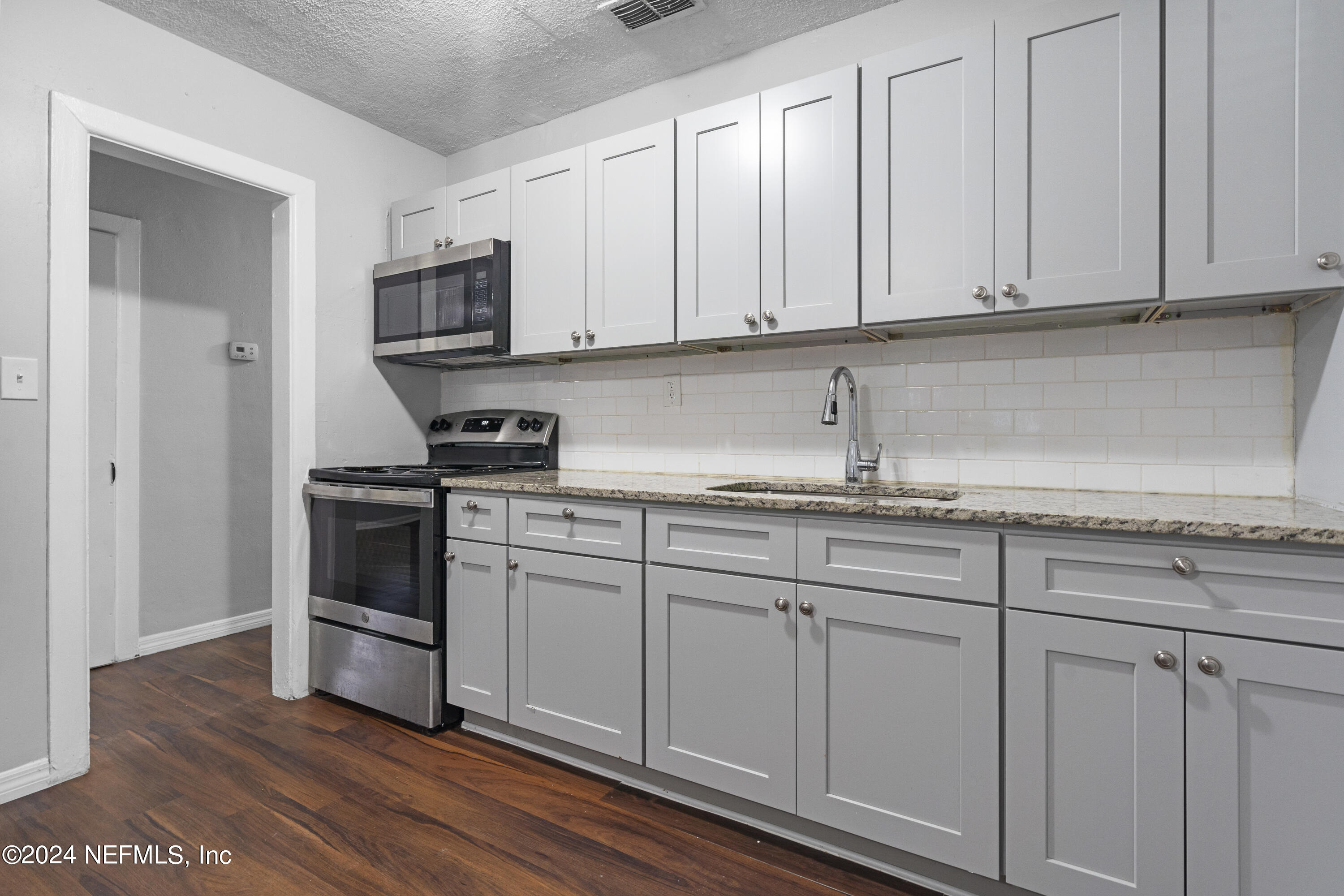 1174 Mohawk Street Jacksonville, FL 32205 - Photo 15 of 33 a kitchen with granite countertop white cabinets and stainless steel appliances