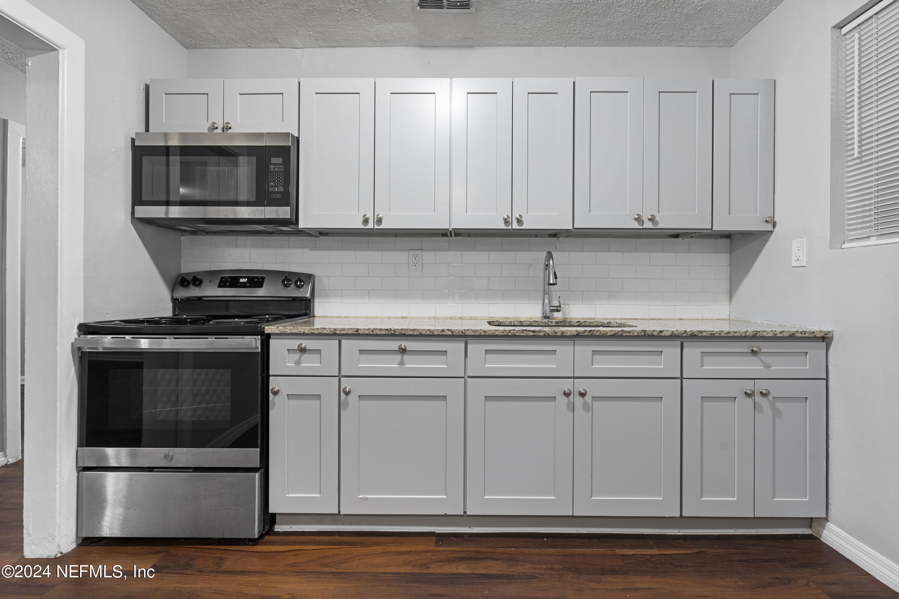 1174 Mohawk Street Jacksonville, FL 32205 - Photo 16 of 33 a kitchen with granite countertop white cabinets and stainless steel appliances