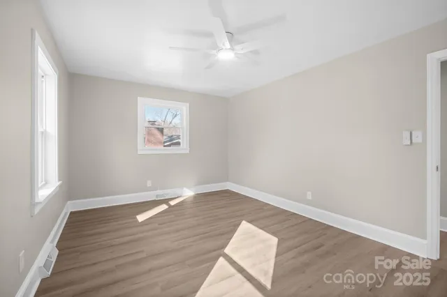 an empty room with wooden floor and windows