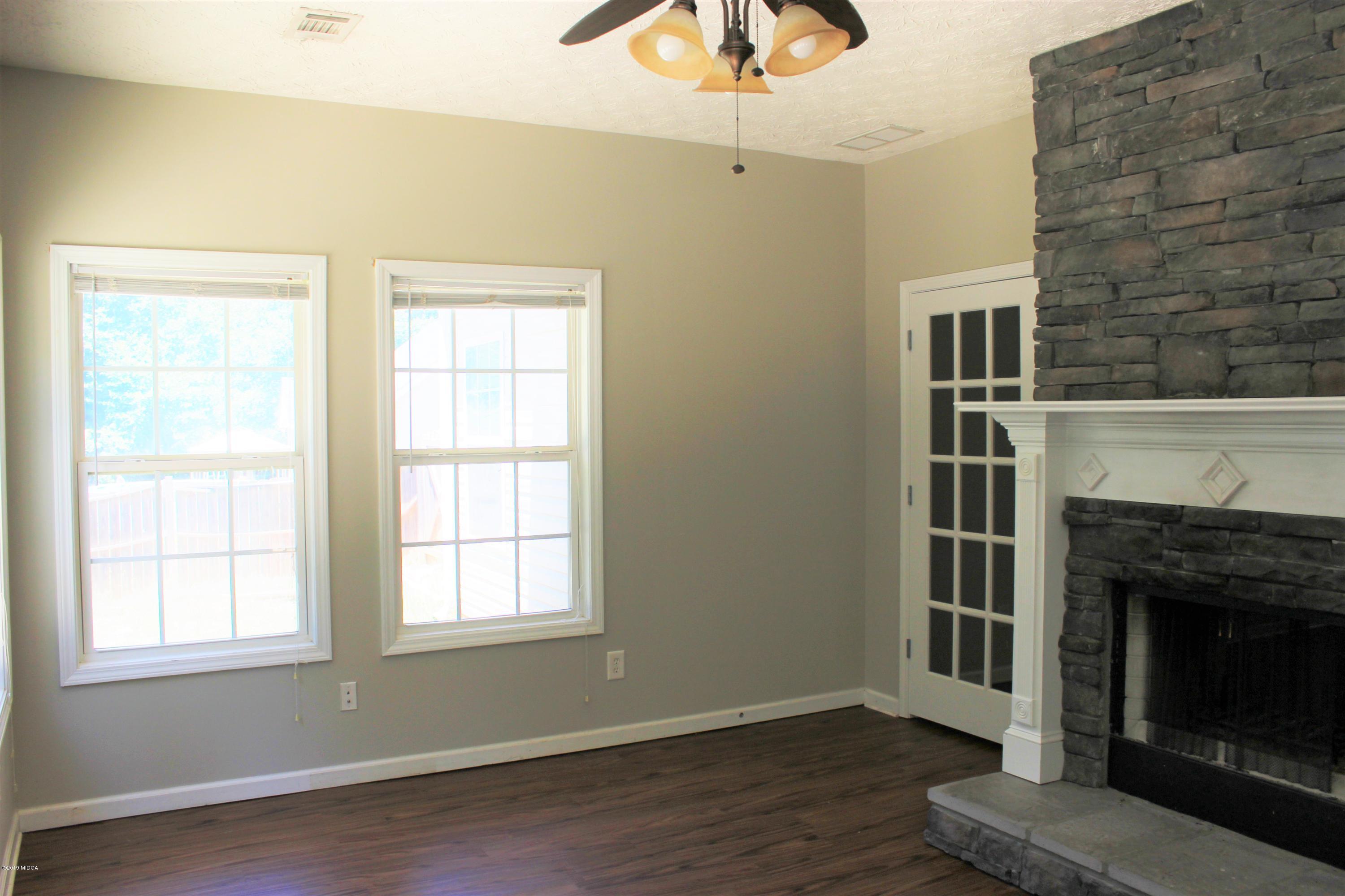 318 Hickory Road Jackson, GA 30233 - Photo 7 of 13 an empty room with wooden floor fireplace and windows