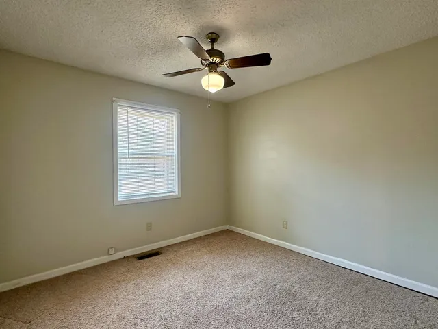 an empty room with a ceiling fan and window