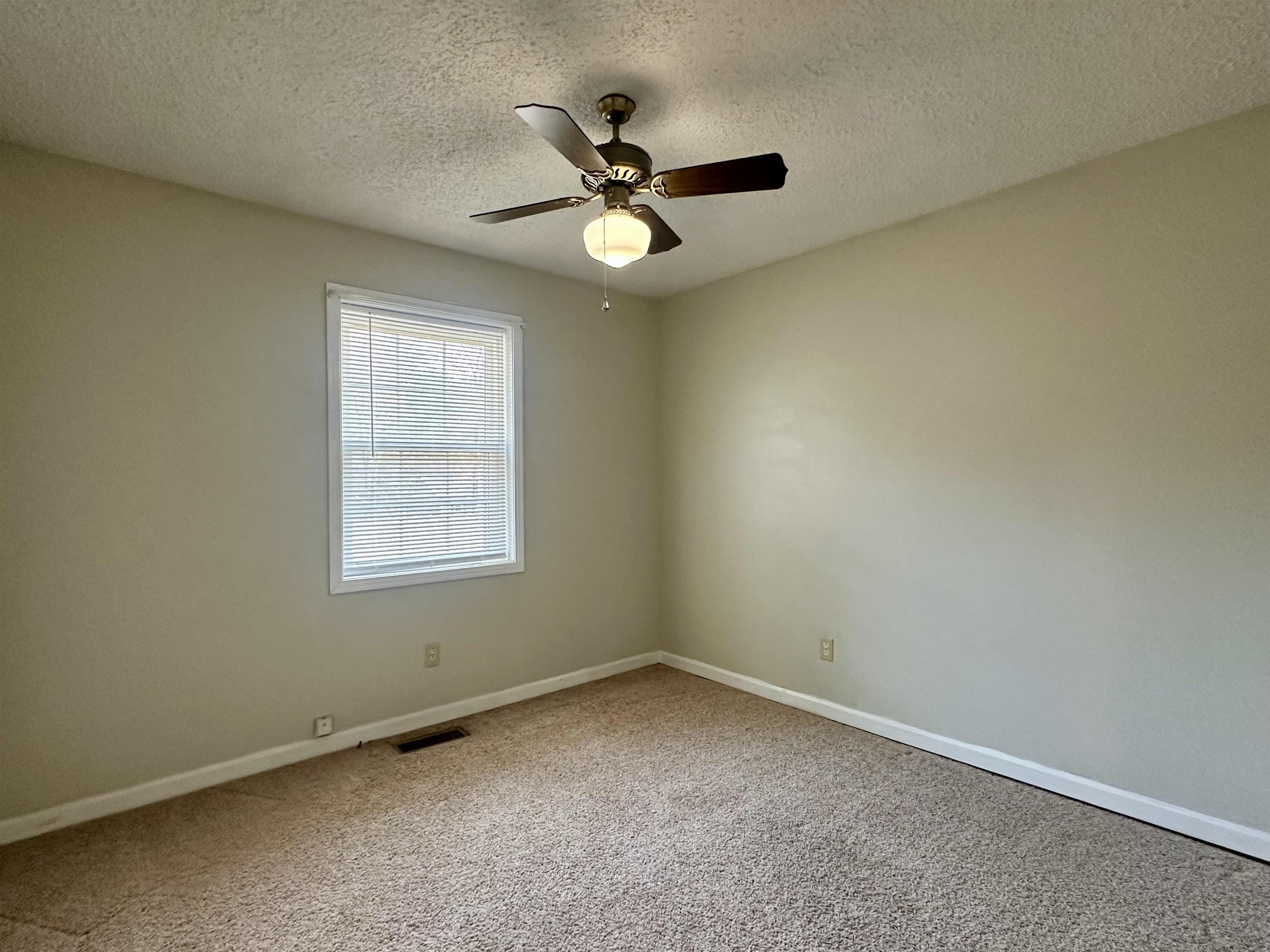 170 Mitchell Street Selmer, TN 38375 - Photo 19 of 26 an empty room with a ceiling fan and window