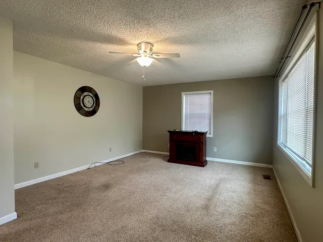 an empty room with windows and fan