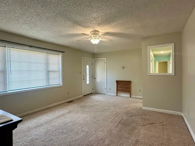 an empty room with windows and fan