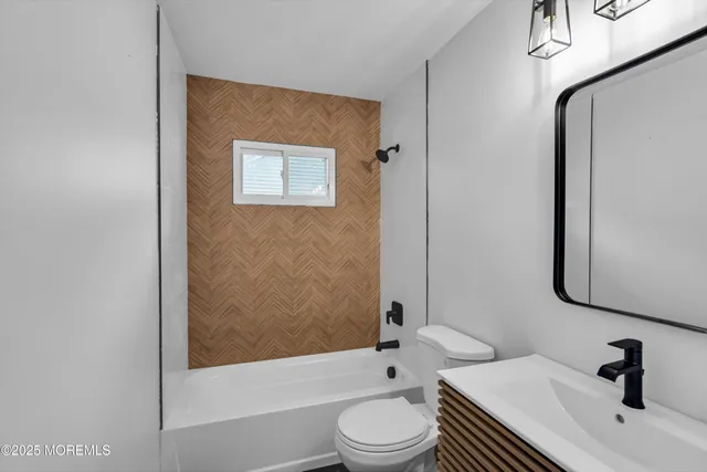 a bathroom with a bathtub shower sink mirror vanity and toilet