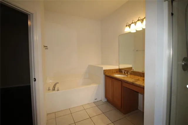 a spacious bathroom with a granite countertop sink a mirror and bathtub
