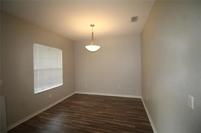 a view of an empty room with window and wooden floor