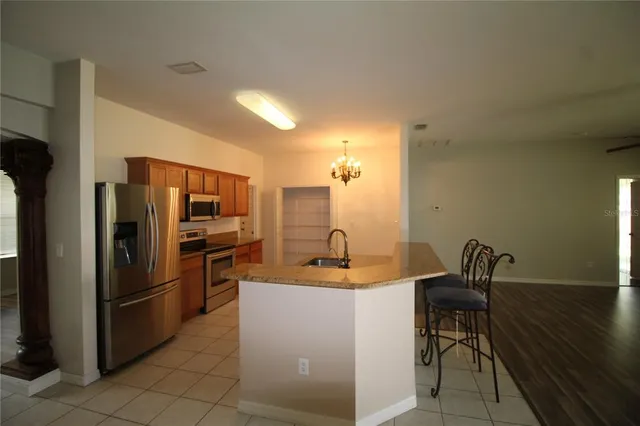 a kitchen with stainless steel appliances kitchen island granite countertop a refrigerator and a sink