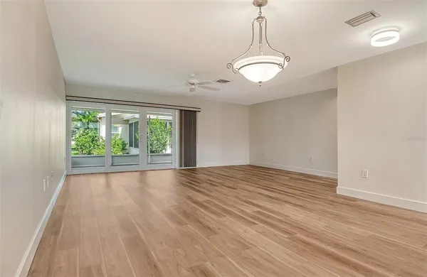 a view of empty room with wooden floor and fan
