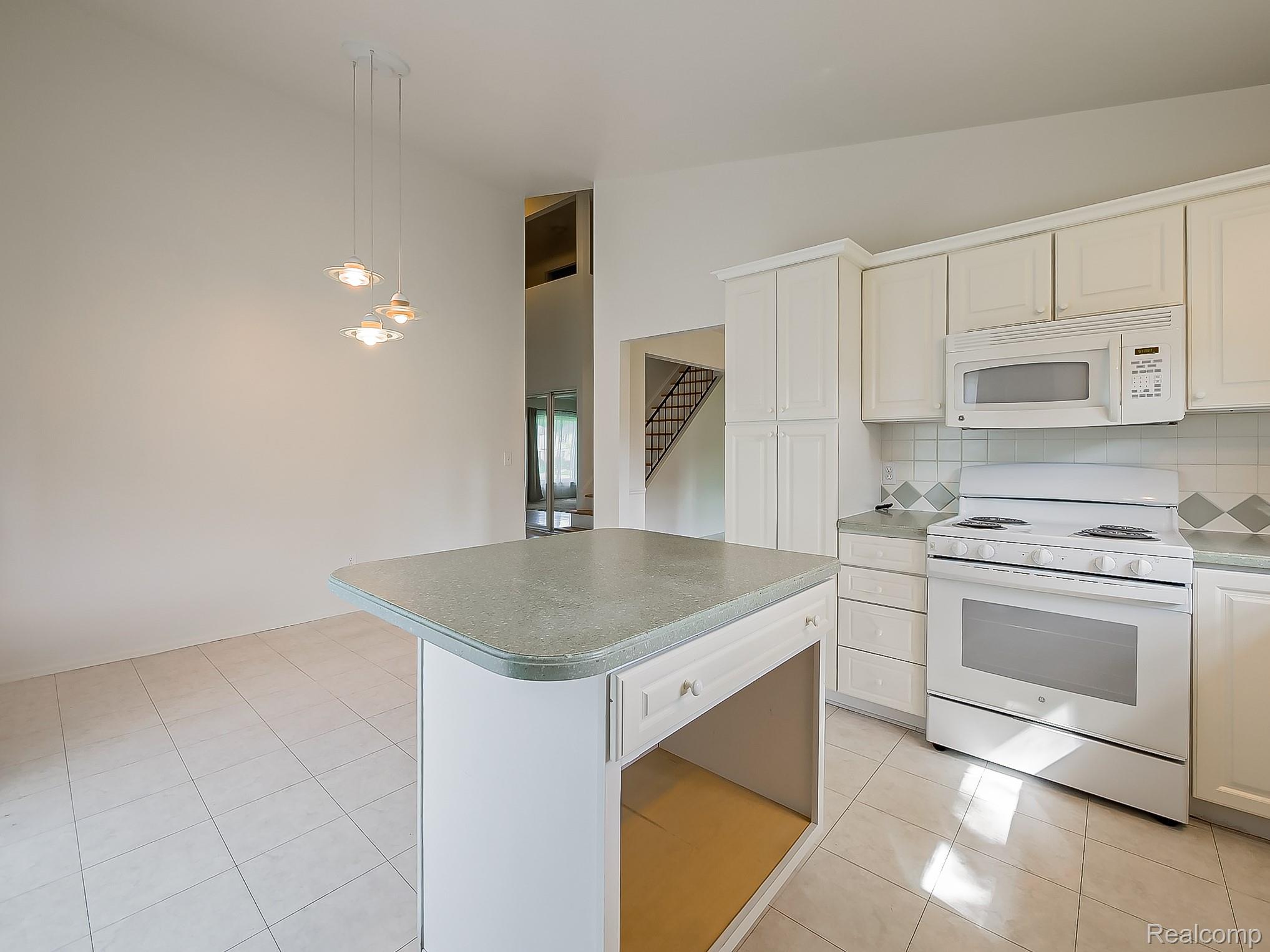 42195 Park Ridge Road Novi, MI 48375 - Photo 3 of 52 Kitchen featuring white cabinetry, a central island with a solid surface countertop, white appliances, and tiled flooring