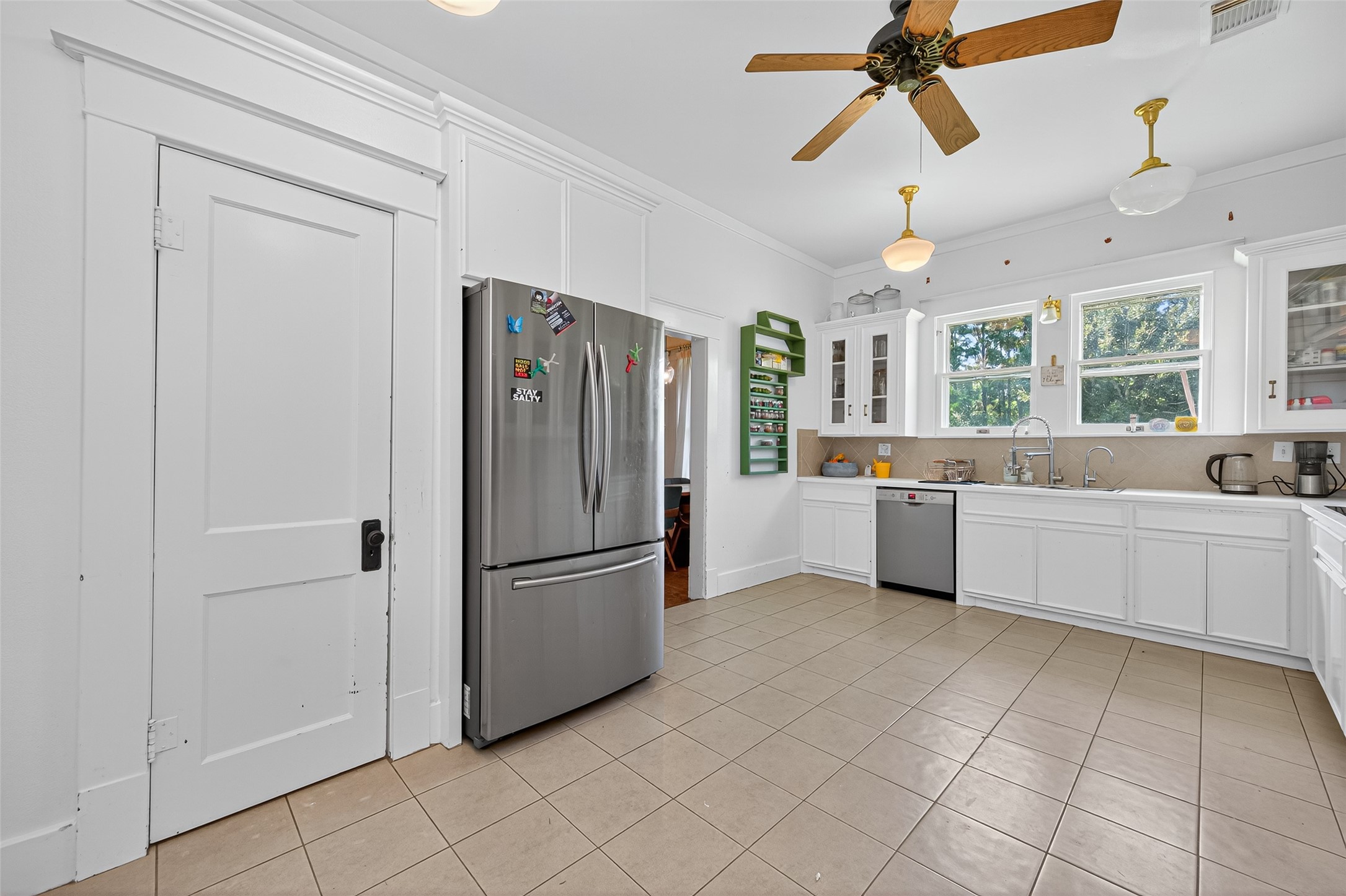38011 Spur 149 Road Magnolia, TX 77354 - Photo 20 of 50 Bright, spacious kitchen with modern stainless steel appliances, ample white cabinetry, and large windows for natural light. Featuring a ceiling fan and neutral tile flooring.