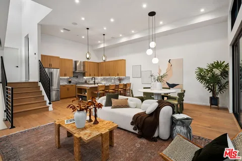 a living room with furniture kitchen view and a chandelier