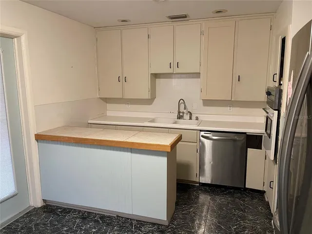 a kitchen with stainless steel appliances granite countertop a refrigerator a sink and white cabinets