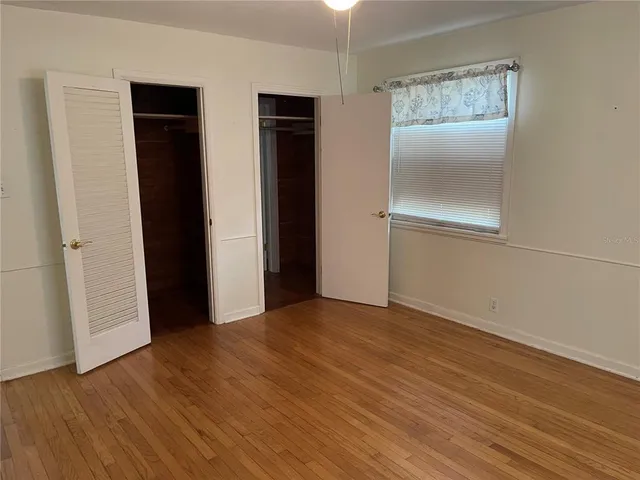 an empty room with wooden floor and closet