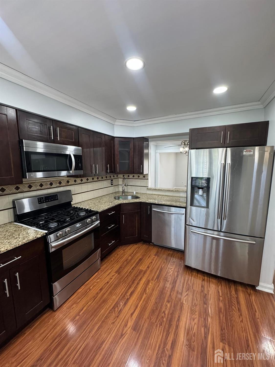 a kitchen with granite countertop stainless steel appliances and wooden floor