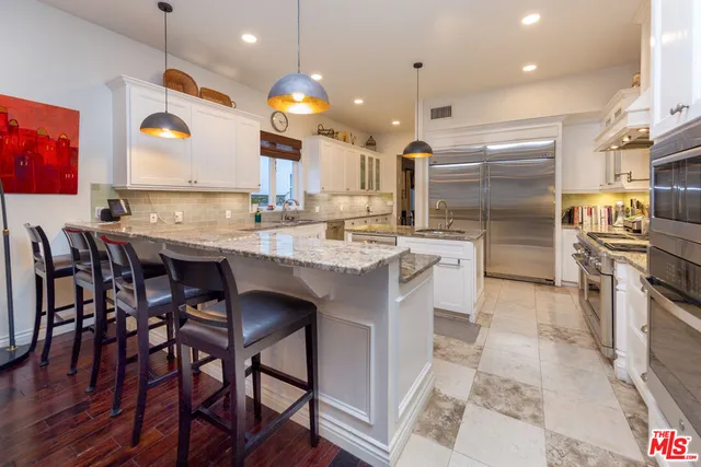 a kitchen with stainless steel appliances granite countertop a sink a stove and a refrigerator