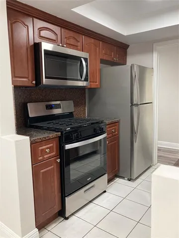 a kitchen with granite countertop a refrigerator and a microwave