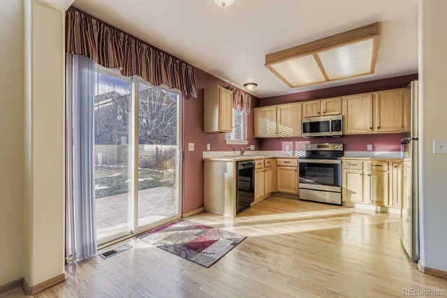 a kitchen with stainless steel appliances granite countertop a stove top oven a sink and a refrigerator