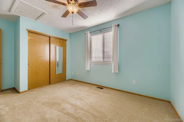 an empty room with chandelier fan and windows