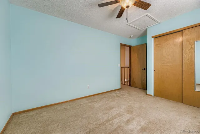 a view of an empty room with a ceiling fan and window
