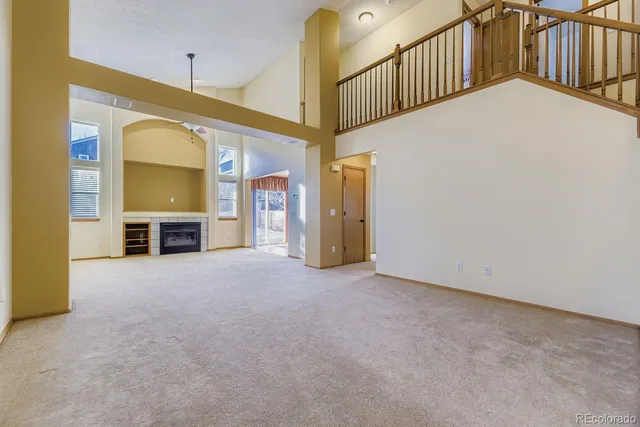 a view of an empty room with a fireplace and windows