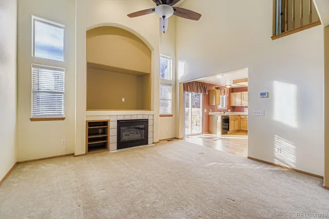 an empty room with fireplace chandelier and windows