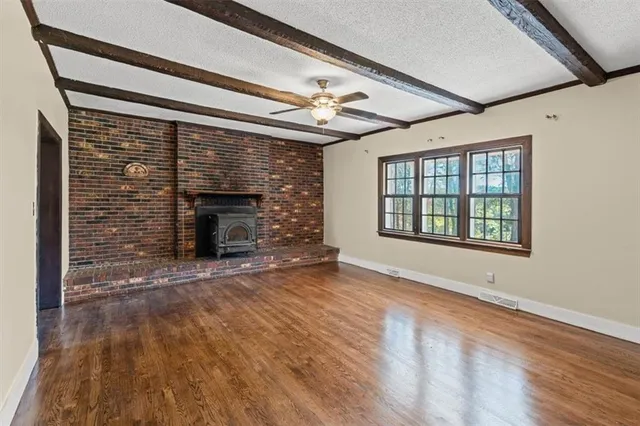 a view of an empty room with wooden floor fireplace and a window