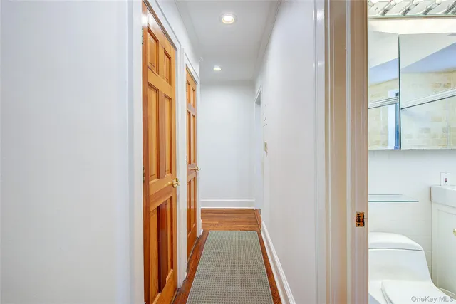 a view of a hallway with wooden floor and a bathroom