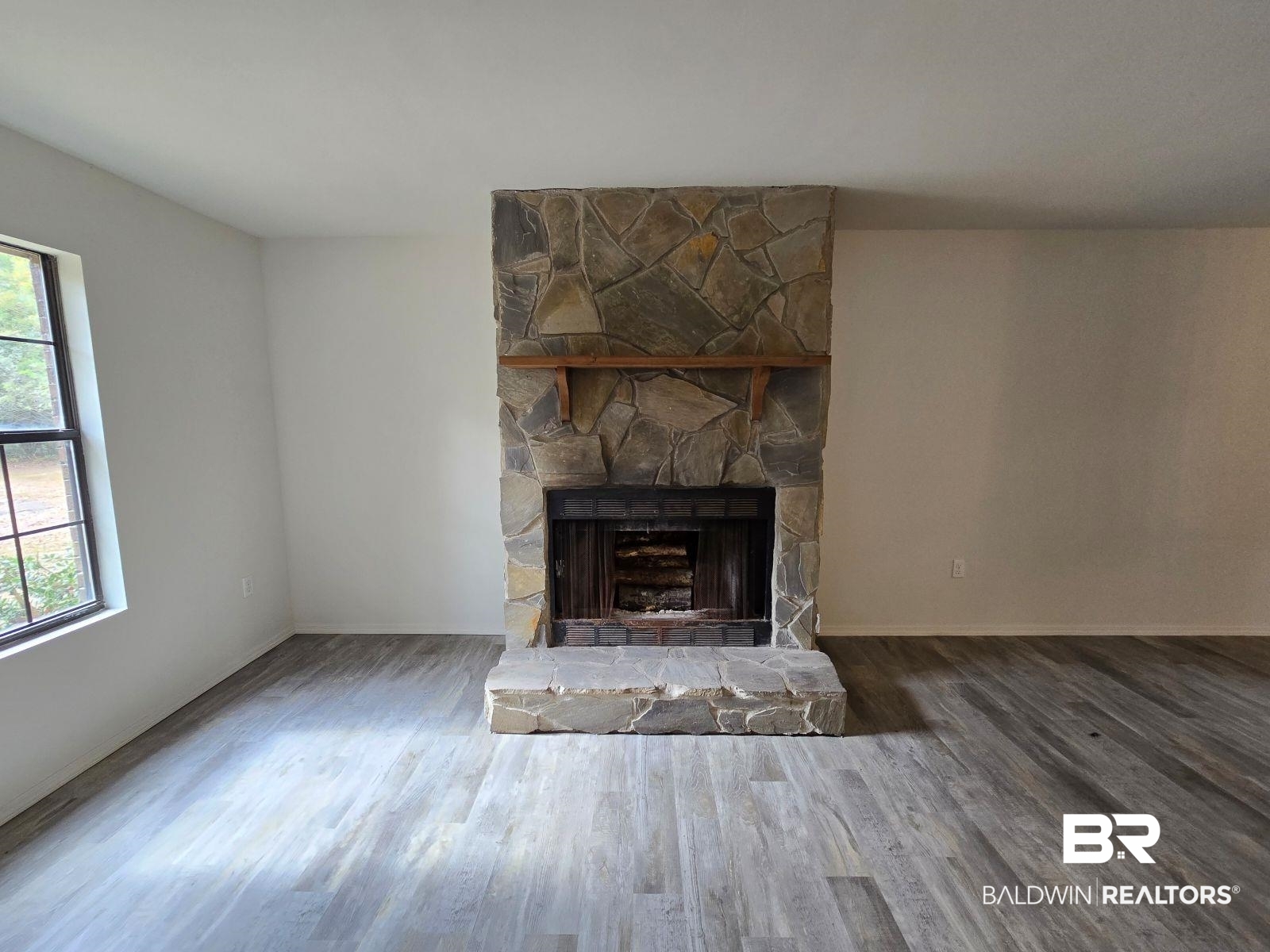 1600 Blair Road Brewton, AL 36426 - Photo 10 of 15 Unfurnished living room with hardwood / wood-style floors, a fireplace, and a healthy amount of sunlight