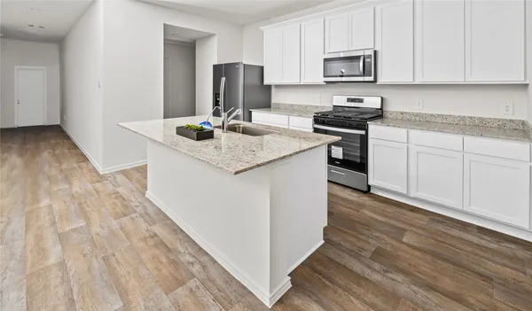 a kitchen with stainless steel appliances granite countertop a stove top oven a sink and white cabinets