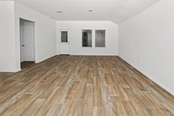 a view of empty room with wooden floor