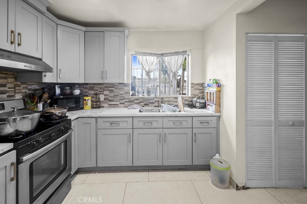 116 North Holly Avenue Compton, CA 90221 - Photo 16 of 23 a kitchen with a sink stove and cabinets