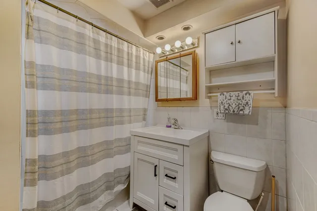 a bathroom with a toilet sink vanity and mirror
