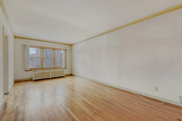 a view of an empty room with a window and wooden floor
