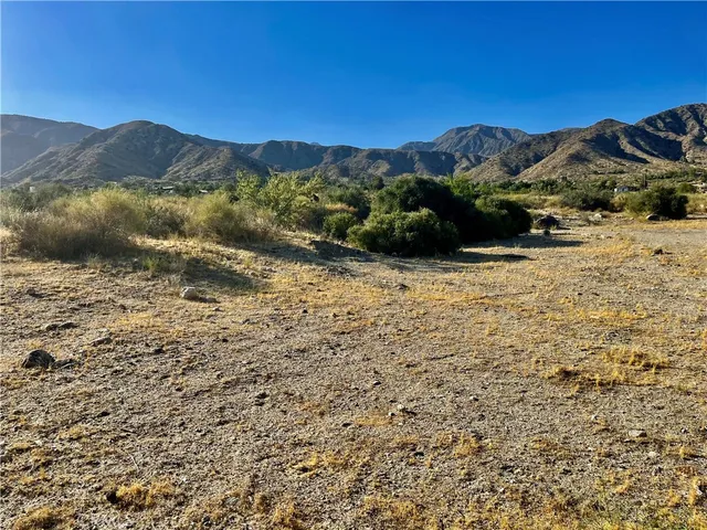 a view of a dry yard with mountains in the background