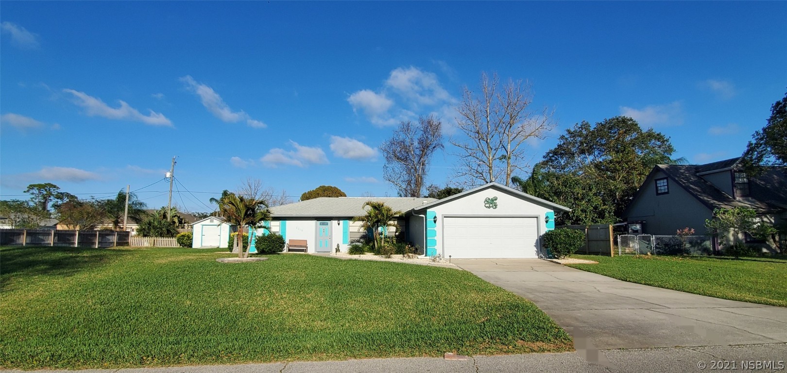 a view of a white house next to a yard with big trees